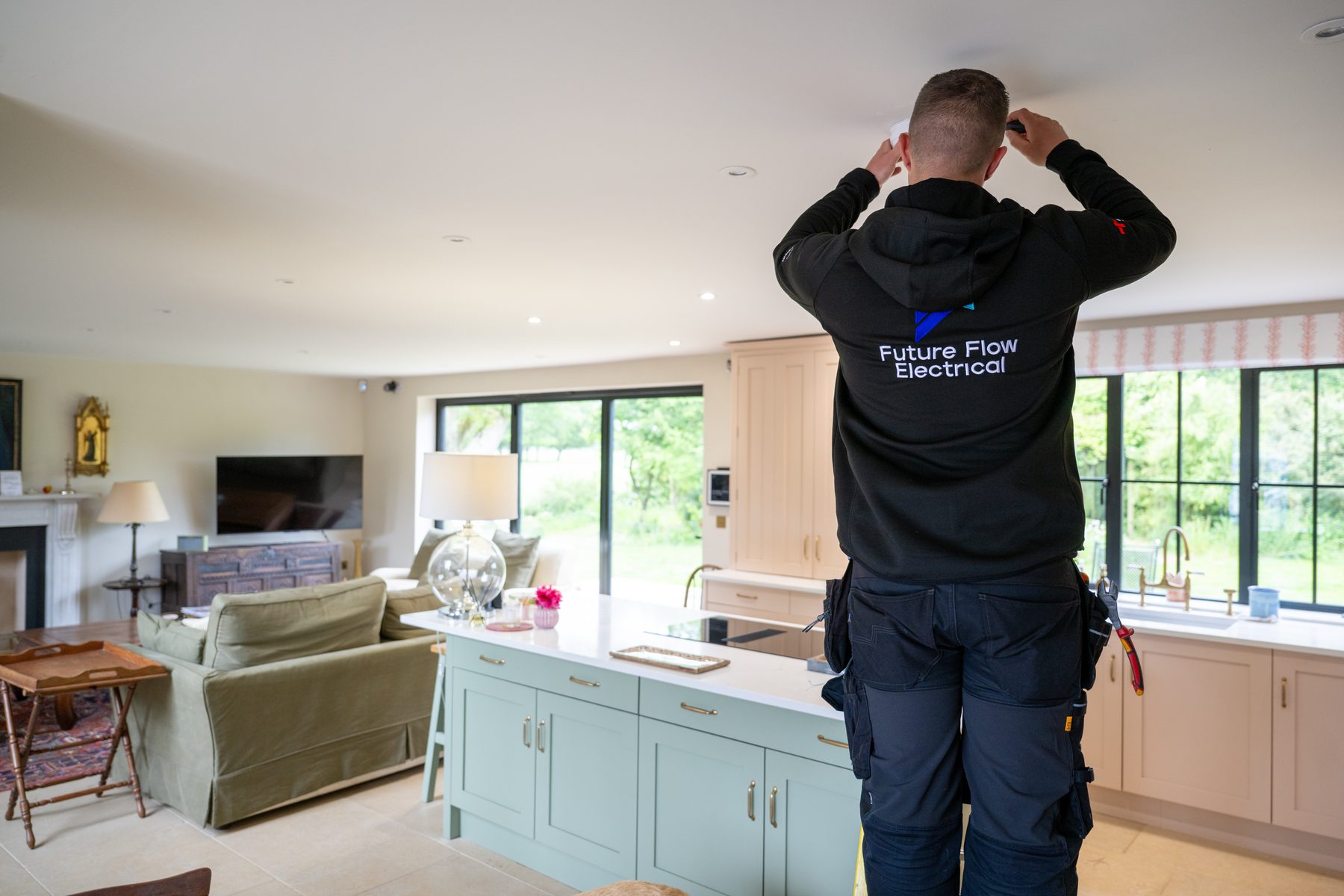 An electrician fitting a smoke alarm in a family kitchen