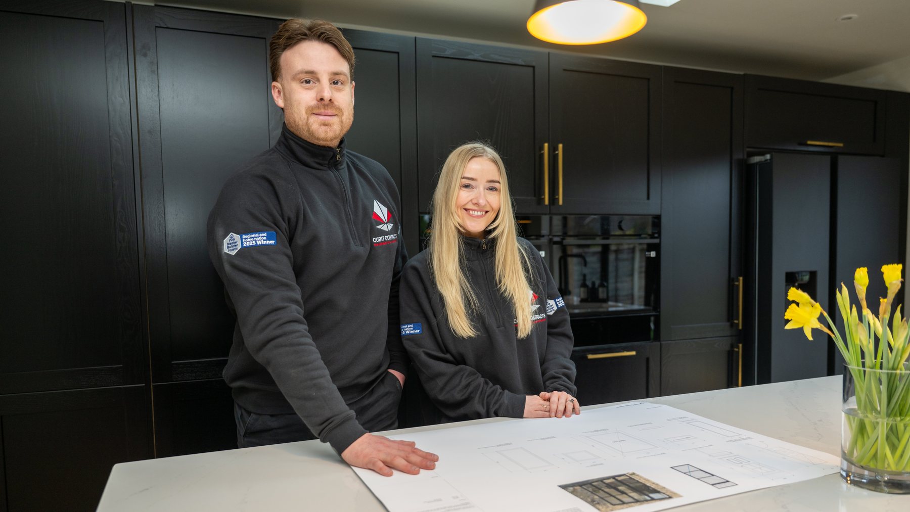Two builders with drawings in a finished kitchen