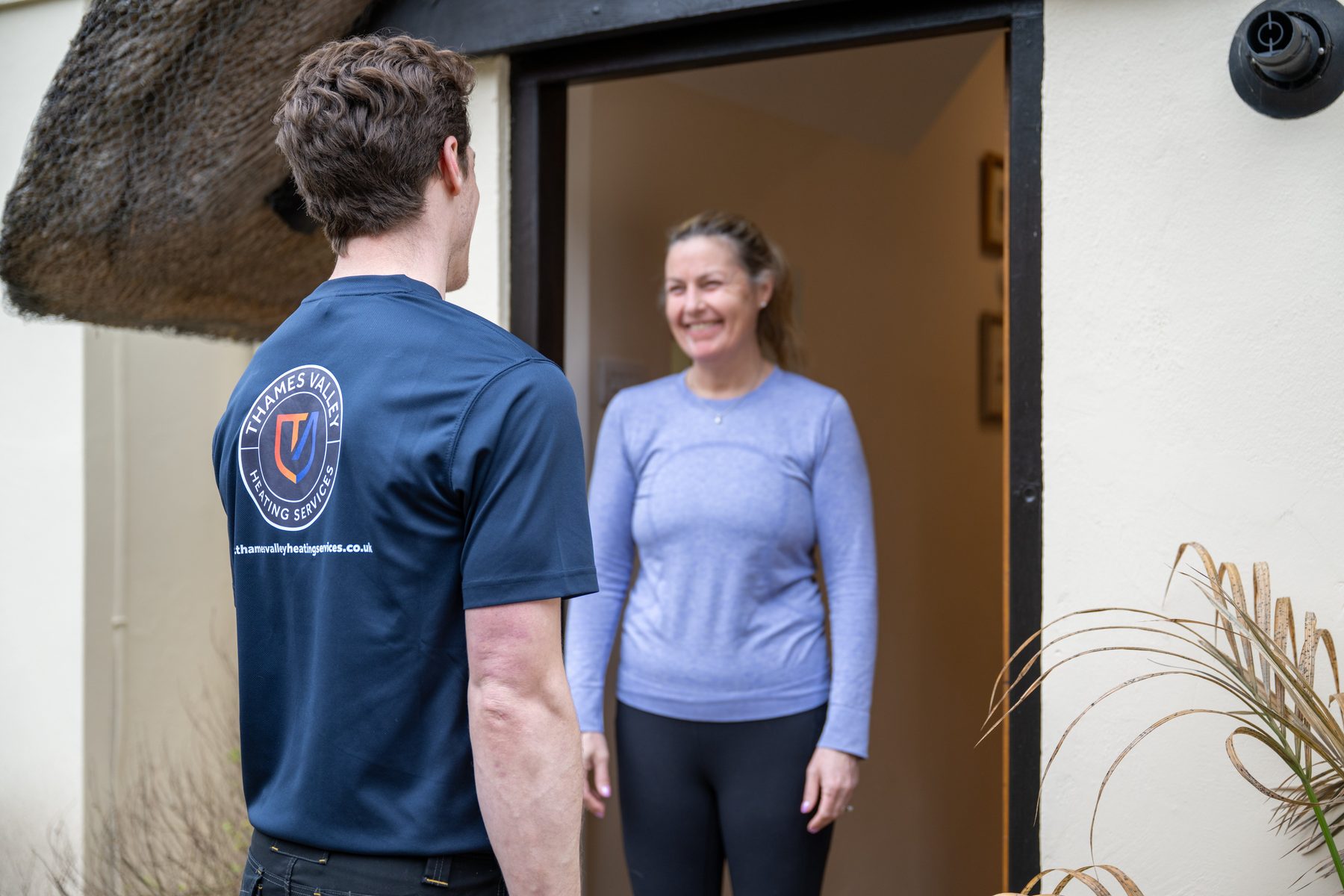 A heating engineer greeting a customer at her door