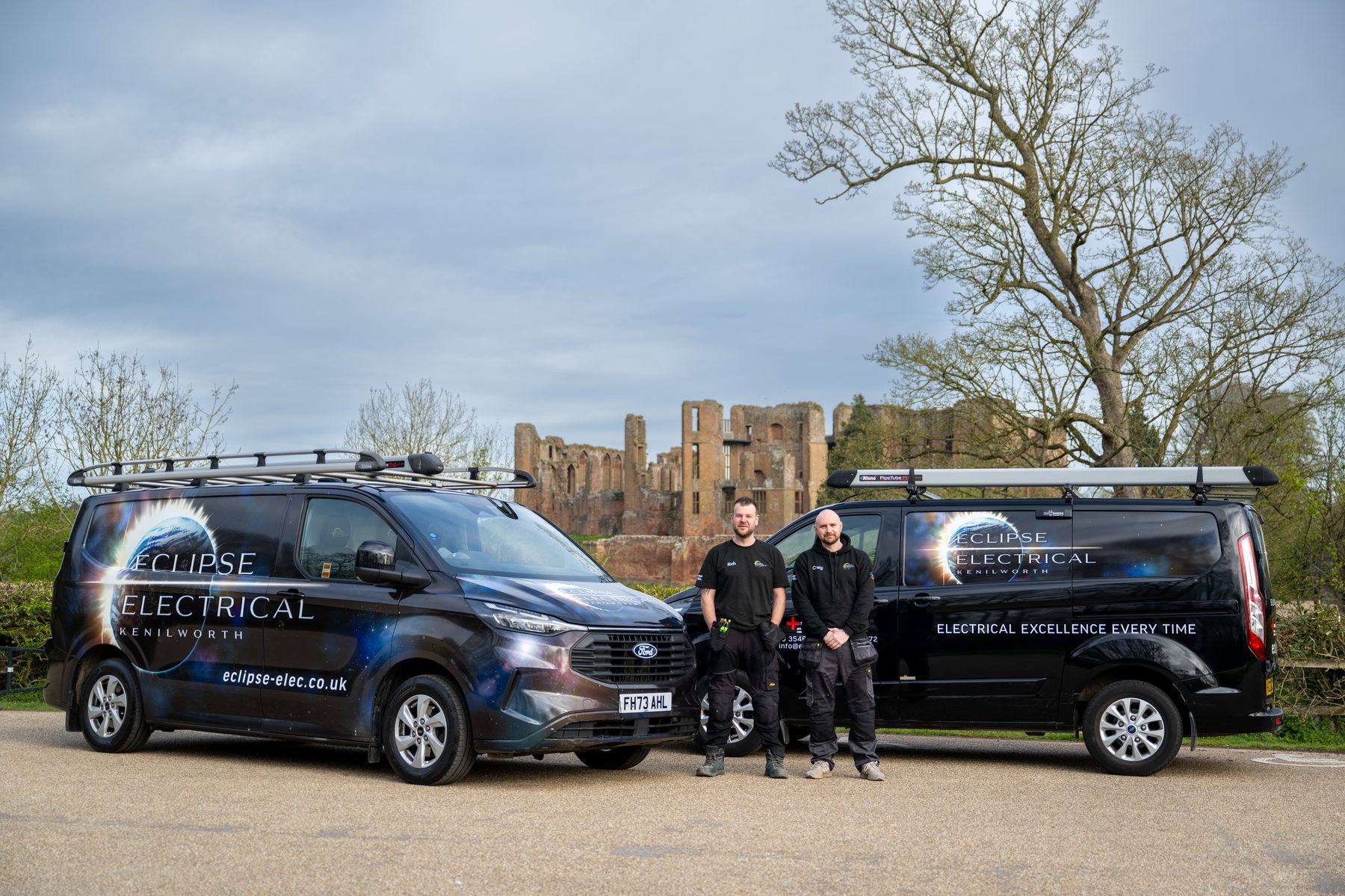 Two electricians photographed with their branded vans