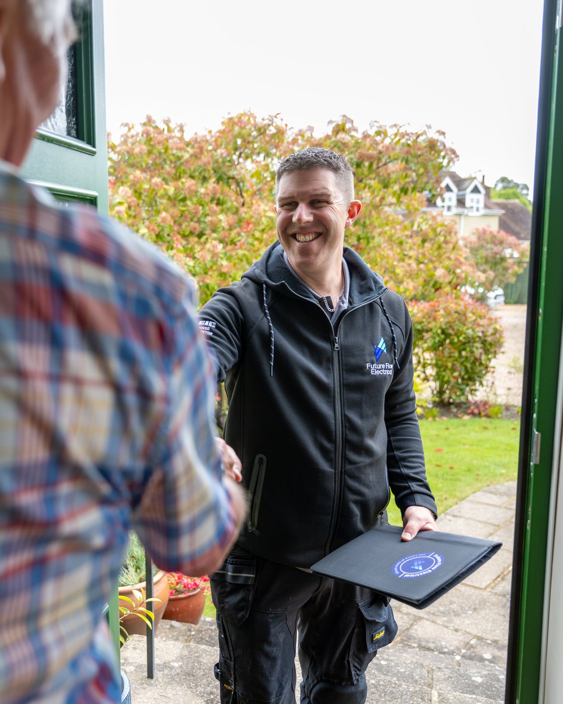 An electrician shaking hands with a customer at the door