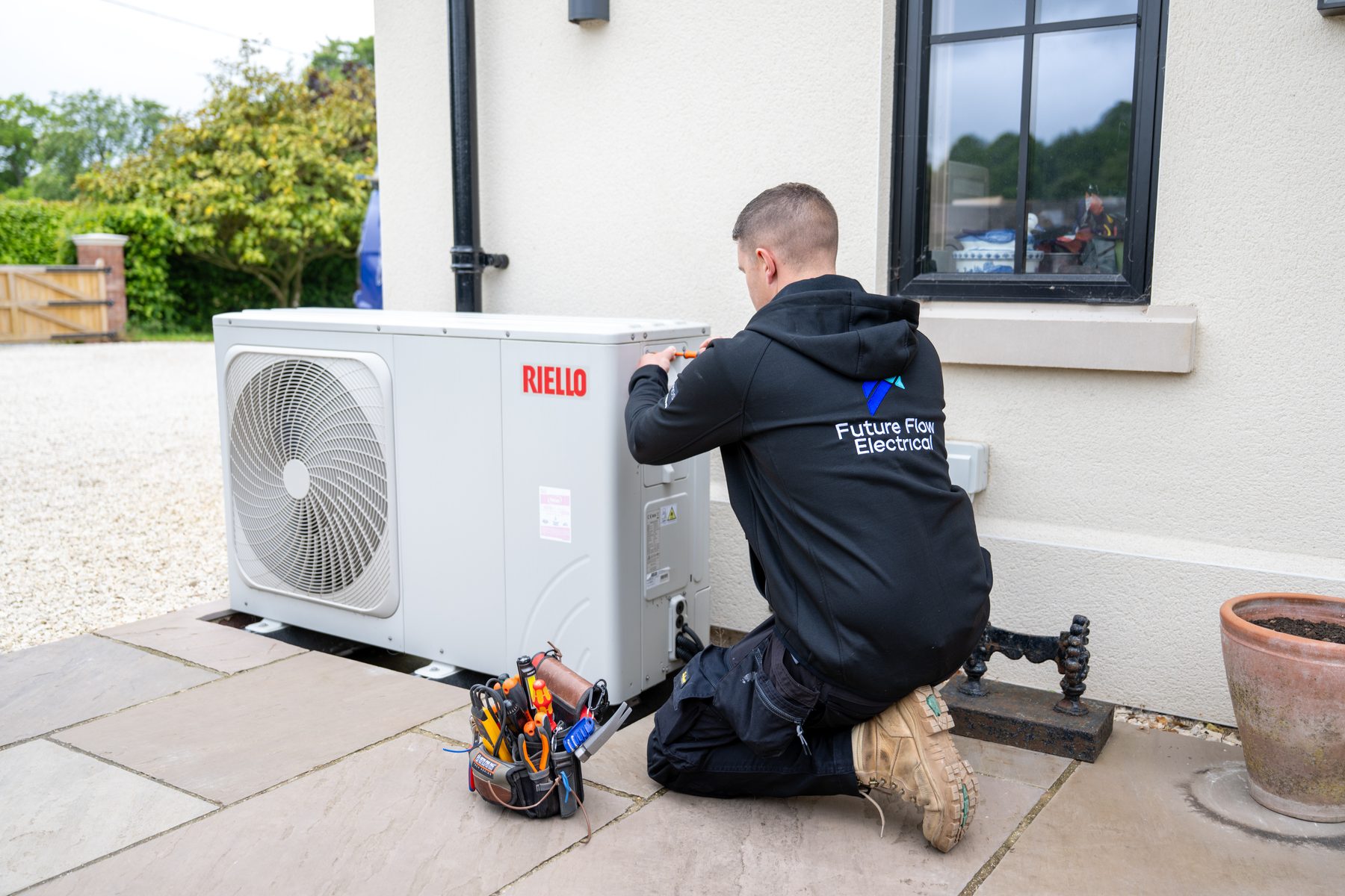 An electrician working on a heat pump unit