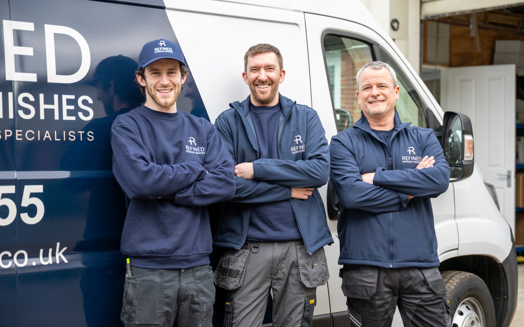 A renovation team photographed together with their van
