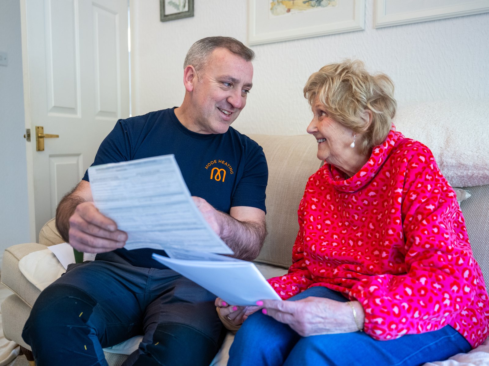 An engineer going through paperwork with a customer in her home